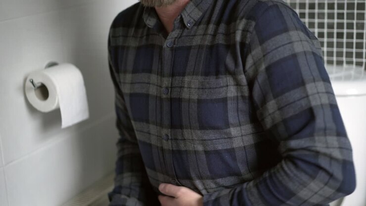 pria sembelit di toilet menggosok perut yang menyakitkan