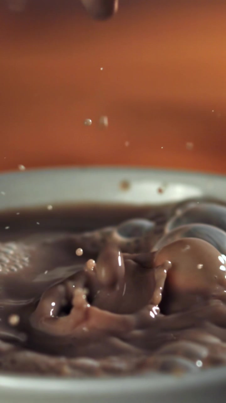 Gocce che schizzano al rallentatore nel latte al cioccolato