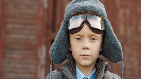 primer plano de un niño pelirrojo poniéndose las gafas de aviador y sonriendo a la cámara