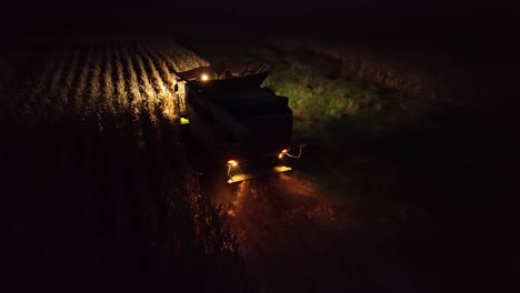 Toma-Aérea-De-Seguimiento-De-Una-Cosechadora-De-Maíz-Por-La-Noche.