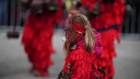 Disfraz-De-Kuker-Búlgaro-De-Un-Niño-Sosteniendo-Un-Martillo-De-Madera-Vestido-De-Rojo-Con-Una-Máscara-De-Oso