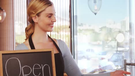 Smiling-waitress-showing-slate-with-open-sign