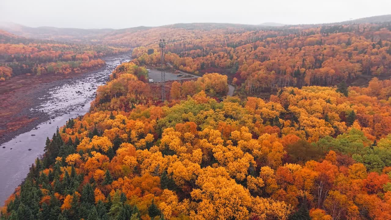 Drone footage shows rugged cliffs and rolling ridges with orange and green foliage