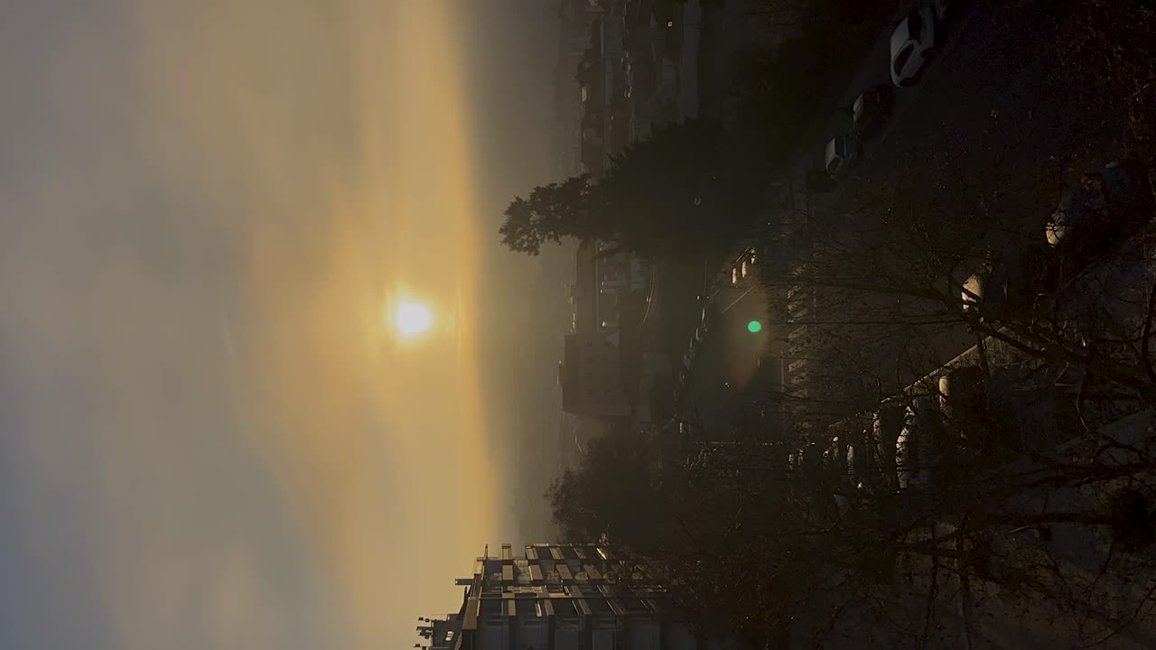 amanecer brumoso sobre los edificios y automóviles de la ciudad de cascais, luz suave de la mañana y nubes en movimiento, time-lapse vertical