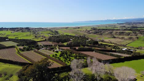 Backwards-aerial-of-stunning-green-coastal-terrain-of-East-Cape-in-New-Zealand