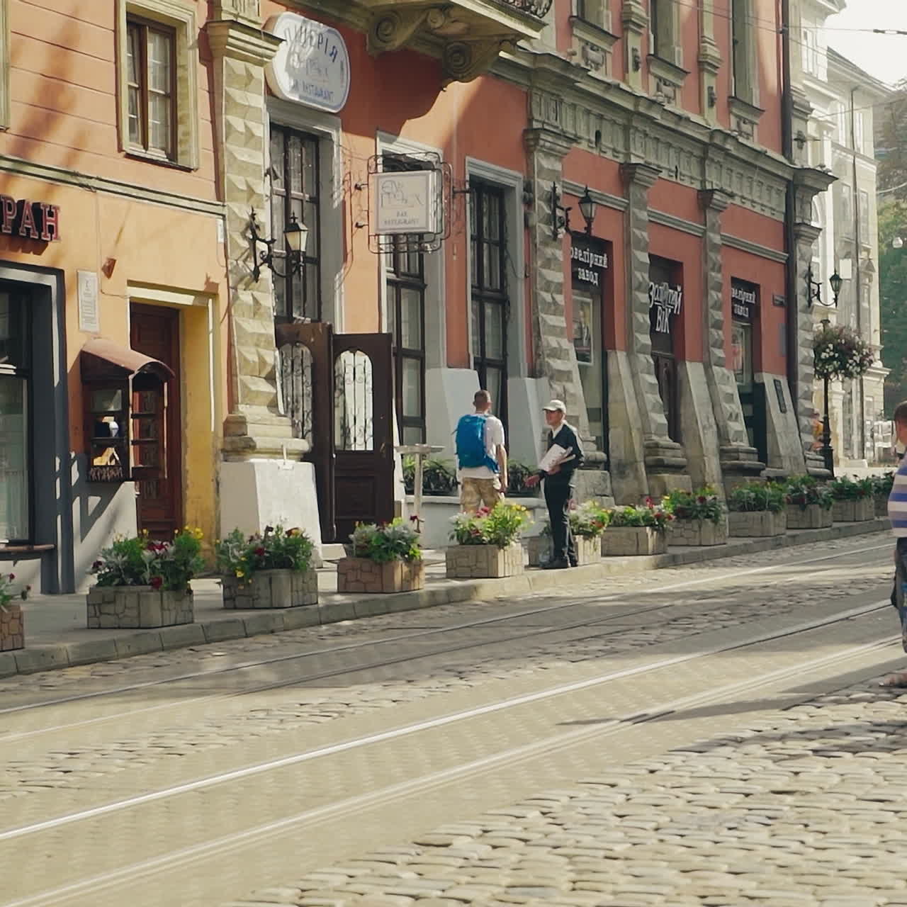 Ancient part of the city Lviv in Ukraine with old buildings, tram and people in the street. Narrow street of historical centre of Europe with tourists and old transport.