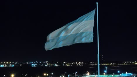 Drone-Volando-Alrededor-De-La-Bandera-Argentina-Ondeando-Por-La-Noche