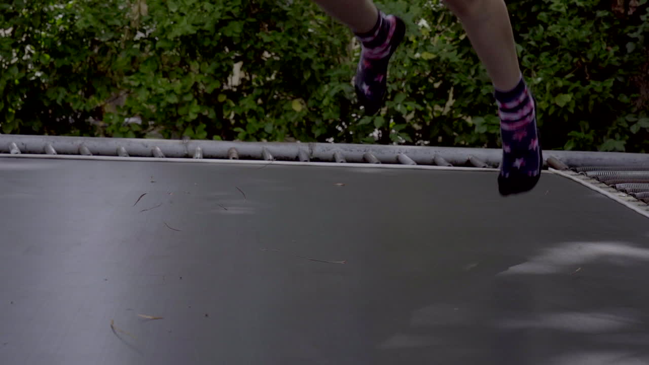 little boy jumping on trampoline in slow motion medium close up of feet and legs