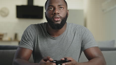 black man playing video game at home. portrait of black guy holding play station