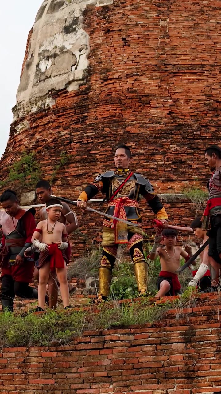 Traditional soldiers in ornate armor stand atop ancient brick ruins under soft daylight.
