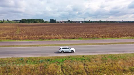 beautiful white car moving on the road. side view of new audi driving on highway on rural fields background under cloudy sky. aerial view.