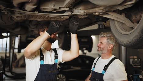 equipo de reparación de automóviles trabajando debajo del automóvil
