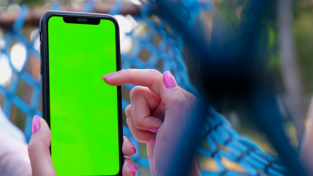 pantalla clave de croma. mujer usa un teléfono inteligente mientras se relaja en la naturaleza