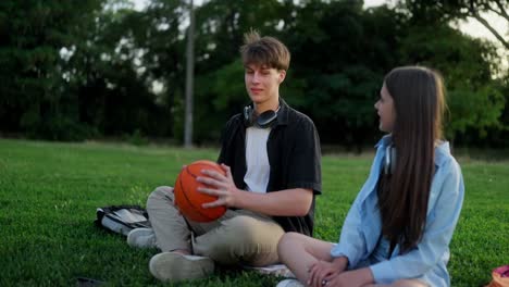 young couple sitting on grass in park and talking