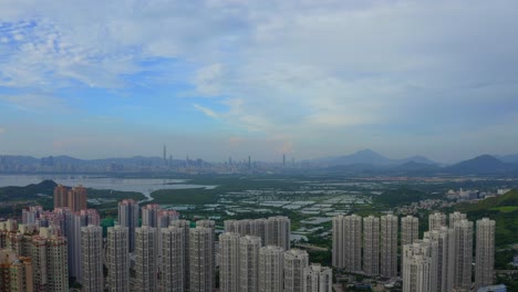 cinematic drone shot traveling downward above a suburb area of hong kong during the day , the distant city shenzen is visible