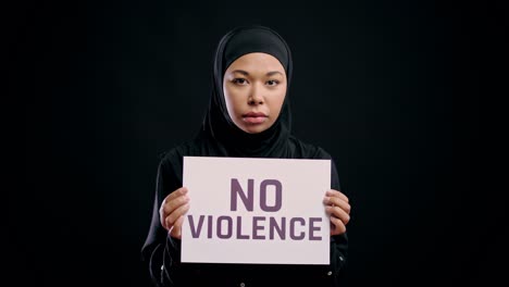 muslim young woman in hijab holding no violence sign, women's rights protection