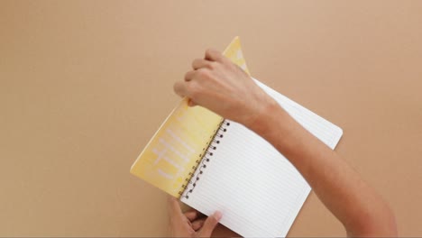 hands removing covers from a spiral notebook, overhead view