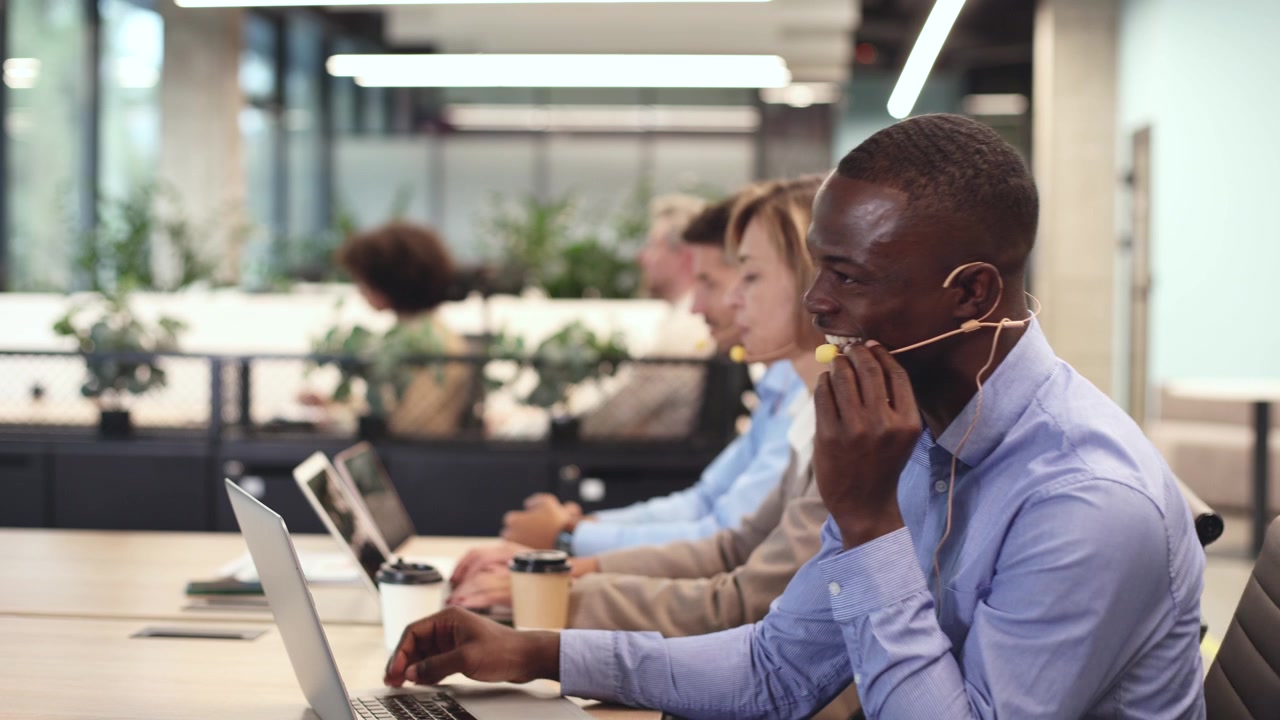African American Call Center Agent Talking on Headset and Typing on Laptop
