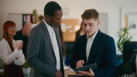 colleagues discussing over digital tablet in office.