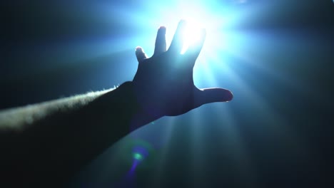 hand reaching out to cover shinning spot light