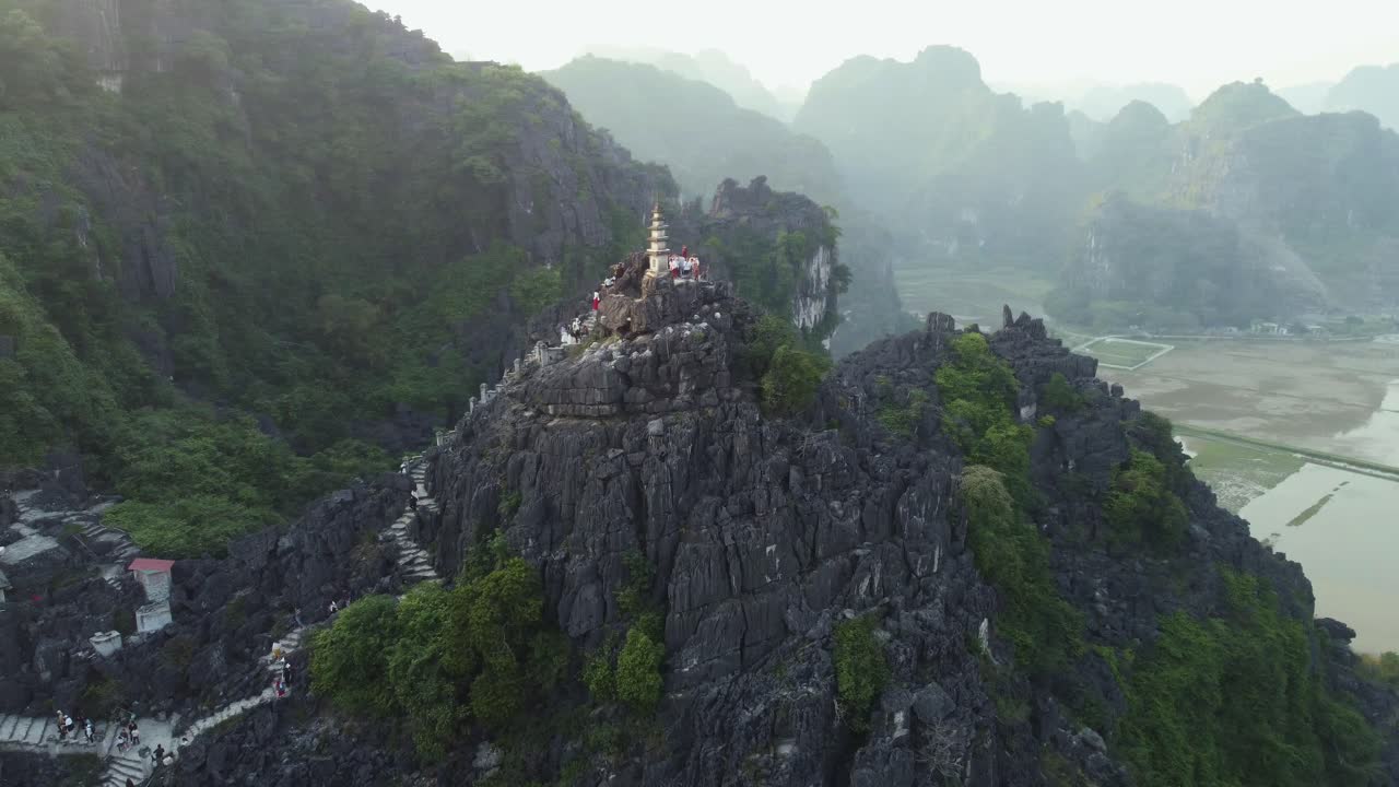 drone aéreo dando vueltas alrededor de una gran montaña de piedra caliza con un pilar del templo en vietnam