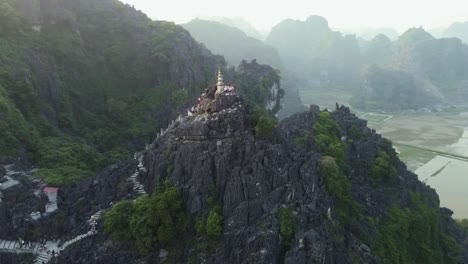 Drone-Aéreo-Dando-Vueltas-Alrededor-De-Una-Gran-Montaña-De-Piedra-Caliza-Con-Un-Pilar-De-Templo-En-Vietnam