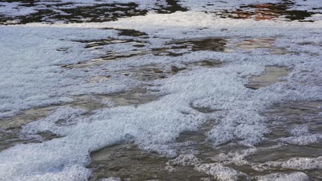 foaming water in rushing over flowing river close to flooding