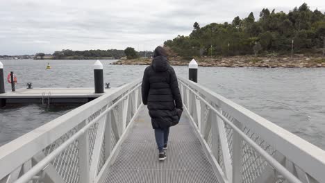 woman in black puffer coat jacket walking at rowntrees dock during winter in barangaroo, sydney, nsw, australia