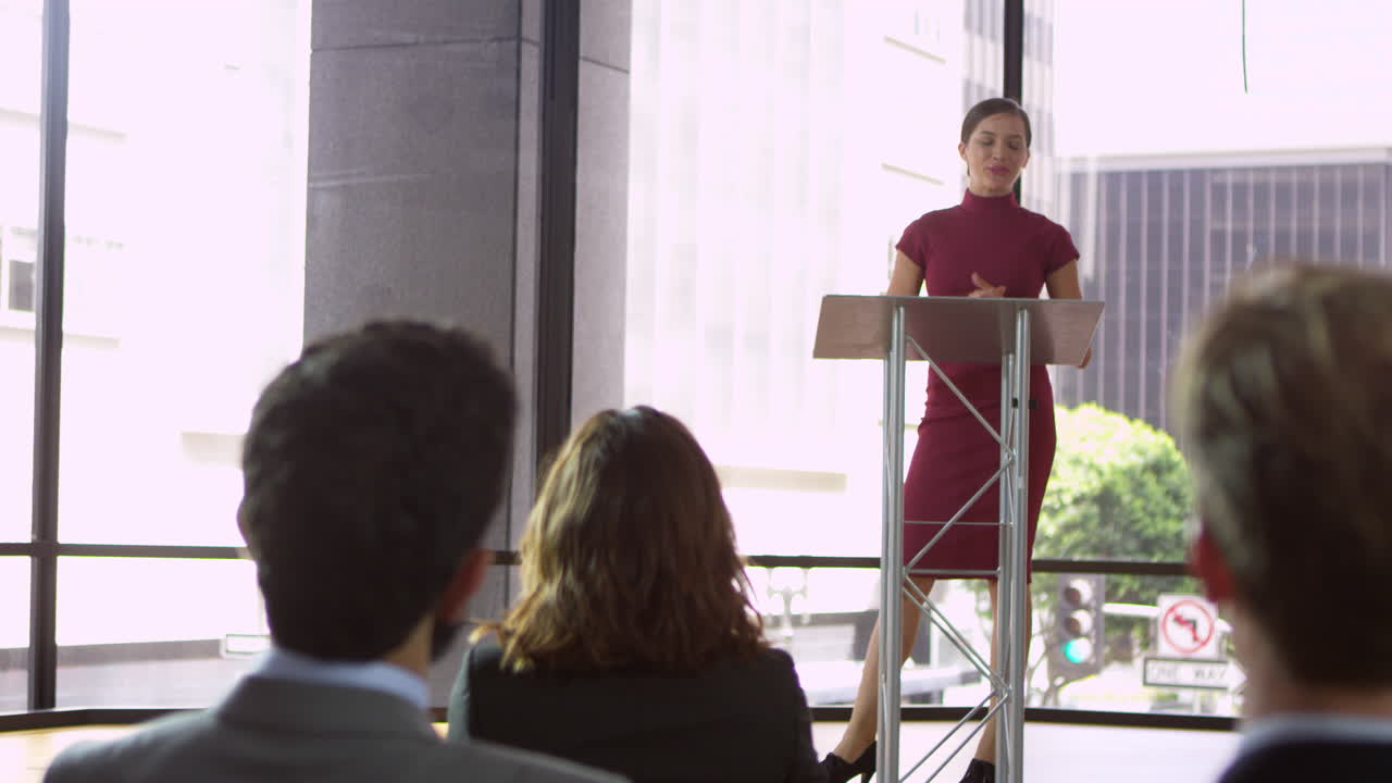Young woman at a lectern presenting a business seminar, shot on R3D