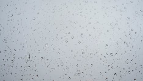 se ve a través de un vidrio de ventana una filmación cercana en cámara lenta de fuertes gotas de lluvia