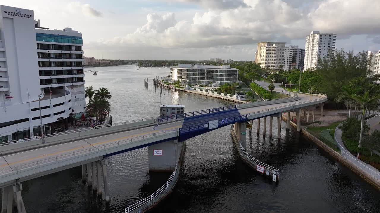 Drawbridge opening and closing over a bustling city canal with boats and waterfront buildings