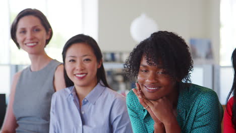 five female work colleagues smiling to camera, panning shot