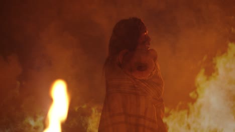 girl wrapped in blanket with teddy bear against fire background
