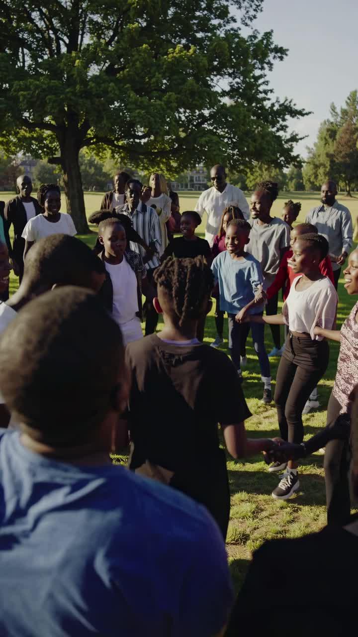 Aerial video captures a joyful group of people in a circle outdoors, with sunlight filtering