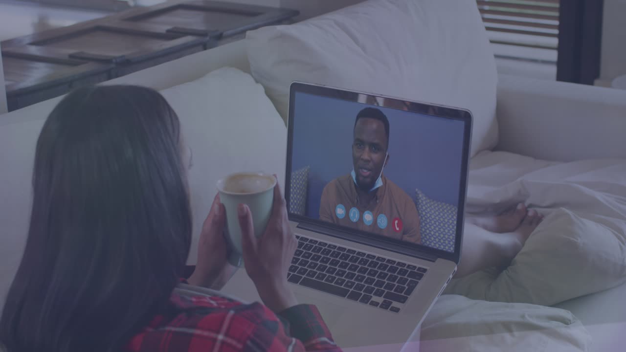Light trails over african american woman holding coffee cup having a videocall on laptop at home
