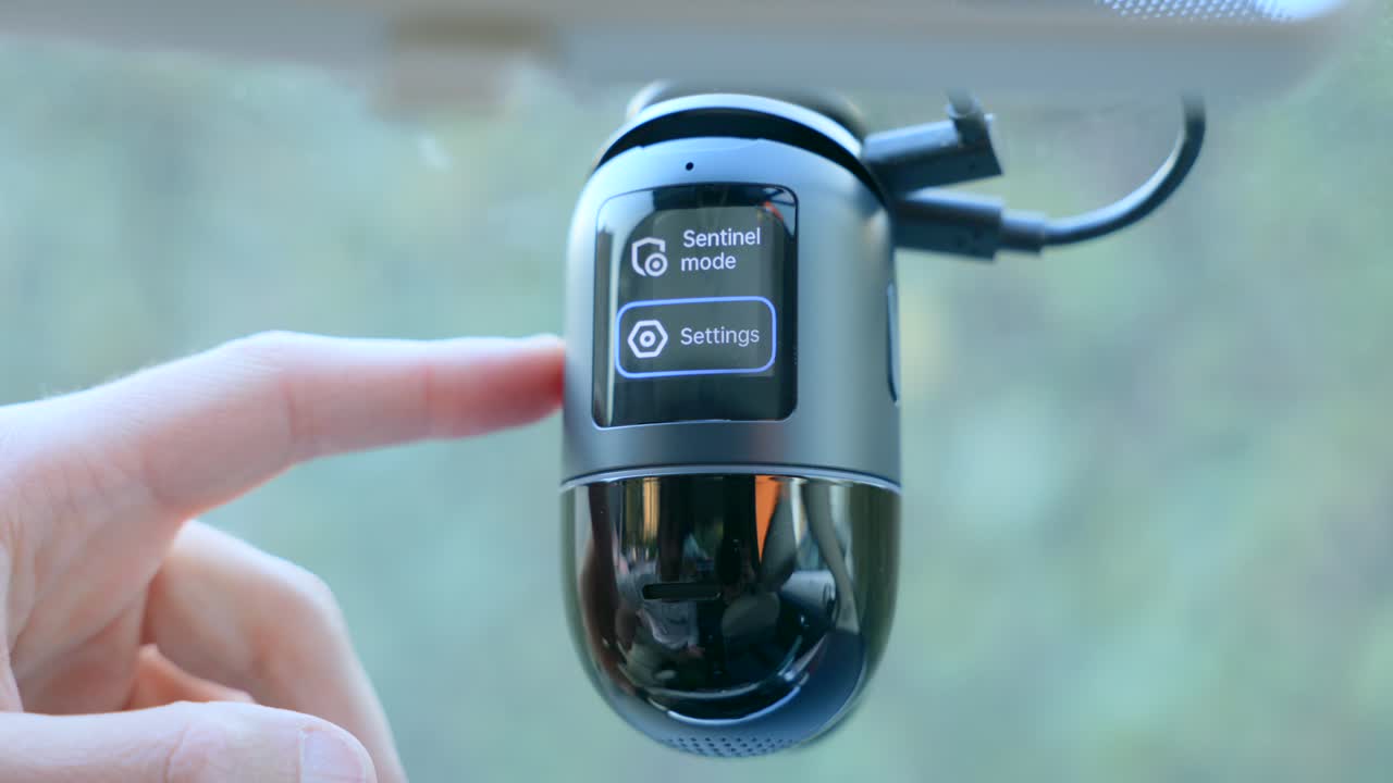 Close-up shot of a modern dashcam being activated, displaying ADAS and remote video functions, highlighting advanced car safety and surveillance technology in action