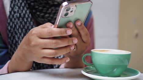 mujer usando un teléfono inteligente en un café, bebiendo café