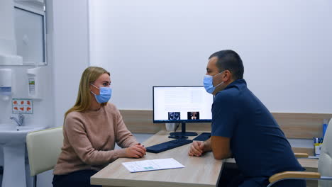 blonde caucasian woman wearing a protective mask talking to the doctor in his cabinet. obstetrician health consultation in clinics.