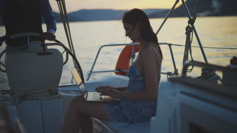 woman working on a laptop on a yacht at sunset