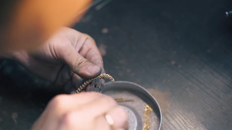 jeweler cuts small parts from gold chain with pliers closeup