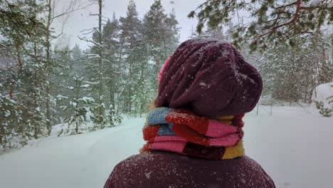 Snowing-in-winter-forest,-woman-looking-around,-snowfall-in-woods