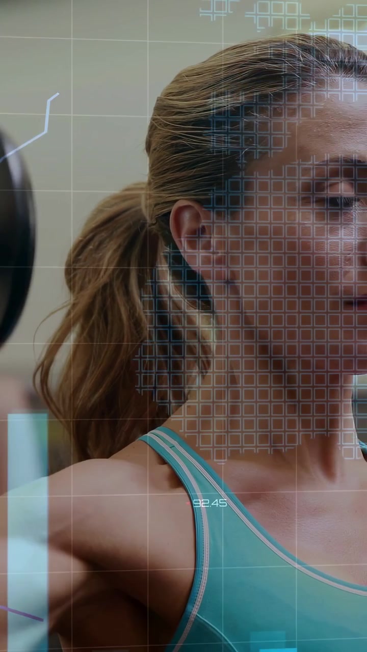 Vertical video: Woman lifting dumbbell in gym as HUD activating, showing grids, charts for tracking