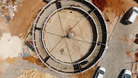 aerial shot above walking animals in a circular outdoor. circle round fence for horse stallion equestrian training animal in a ranch yard at countryside daytime.