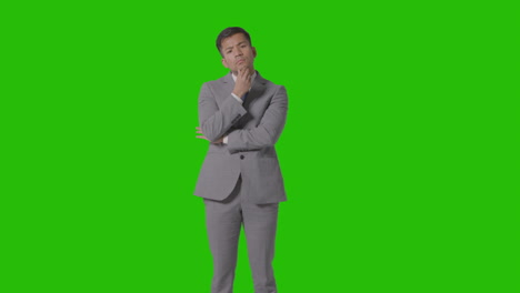 three quarter length shot of serious businessman in suit thinking against green screen