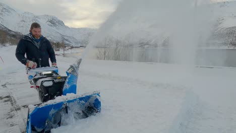 man removing snow on a very cold winter day in northern europe with a snow blower, static shot