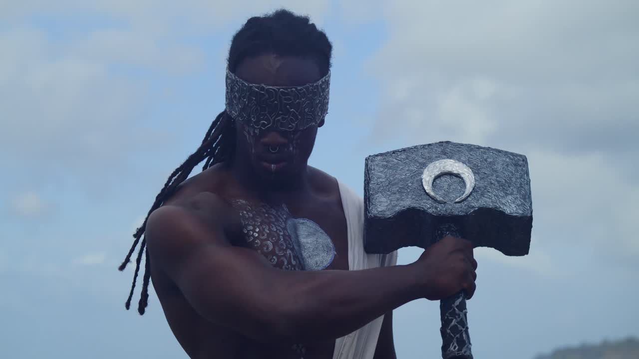 At a tropical beach, a muscular, dark-skinned man expertly brings Nekharis to life through cosplay