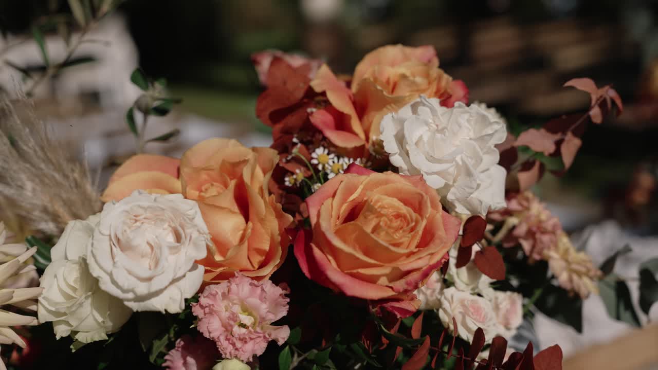 Close up of peach and white roses with greenery and dried elements in natural light