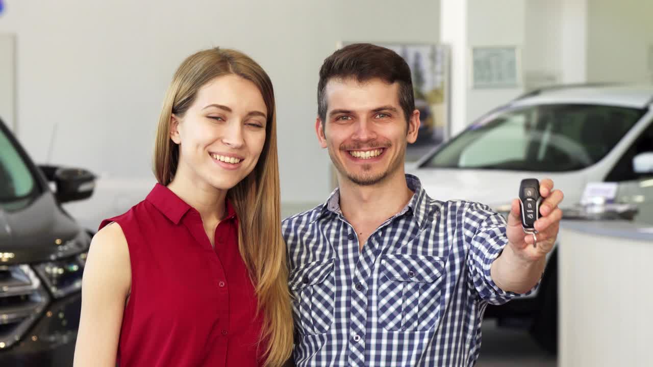 una pareja feliz posando con las llaves del coche de su nuevo auto