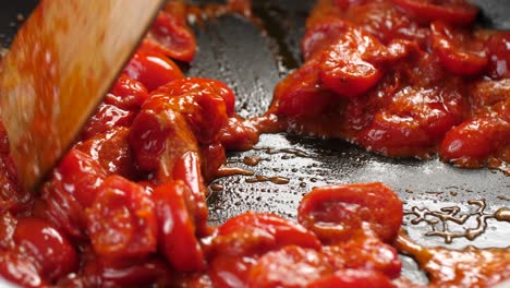 Close-up-shot-of-thick-tomato-sauce-bubbling-in-hot-pan,-wooden-spatula-splitting-sauce-into-two-sides-of-pan