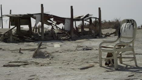 ruinas de edificios, madera y sillas abandonadas en la arena del desierto